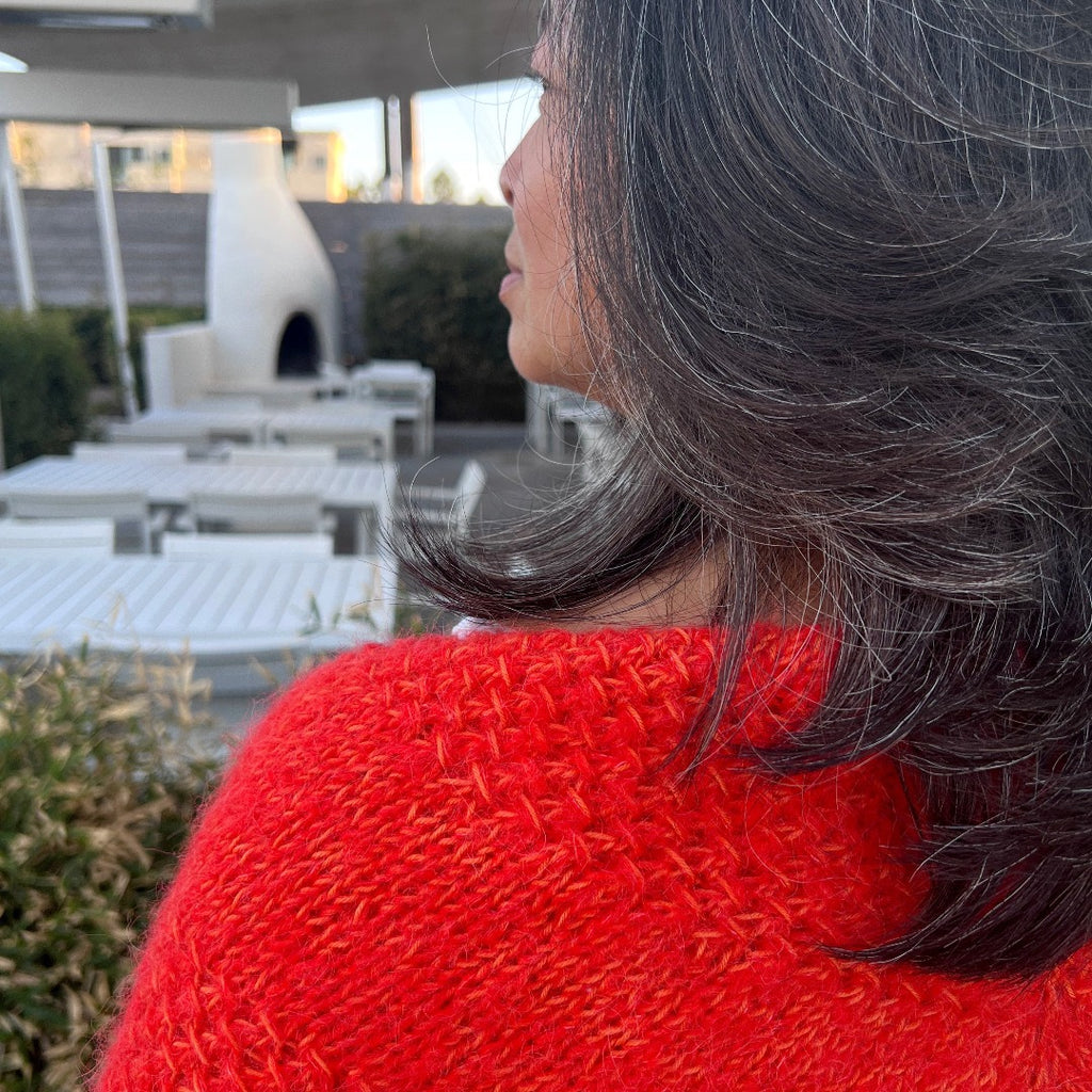 Close up of model wearing orange knitted Textured Shawl in courtyard