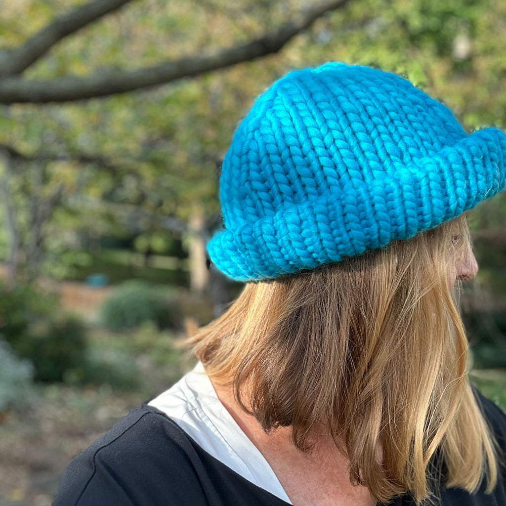 Woman wearing blue "Hey Boo Beanie" hat with brim folded up.